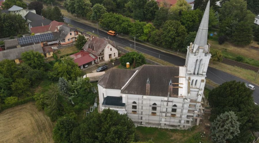 Scenic aerial shot of a church in Tiszavasvári, Hungary, surrounded by lush greenery and town buildings.
